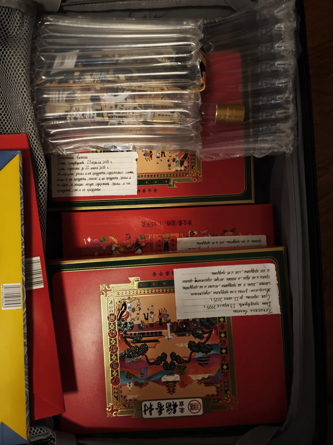 一个打开的行李箱内装有多个包装精美的物品。物品上有中文标签和图案装饰。行李箱内部结构清晰可见。