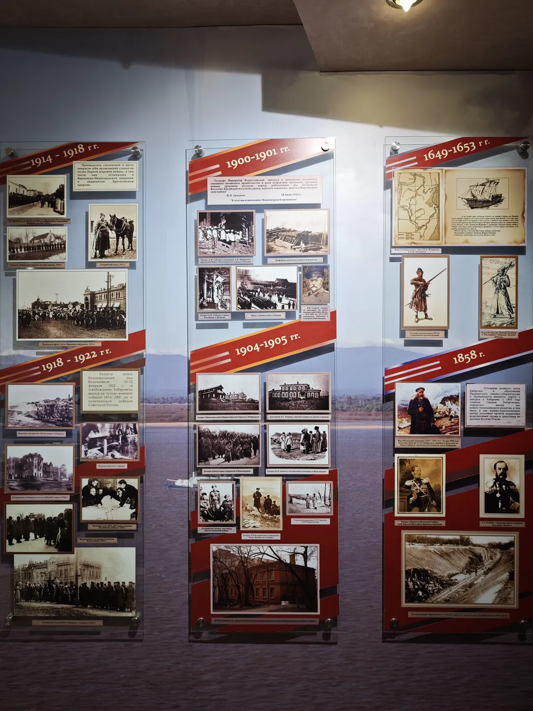 三块展板展示了不同年份的历史照片和信息,包括1914-1918年、1900-1901年和1649-1653年。每块展板上有多个黑白照片和相关描述。展板背景为红色和白色。