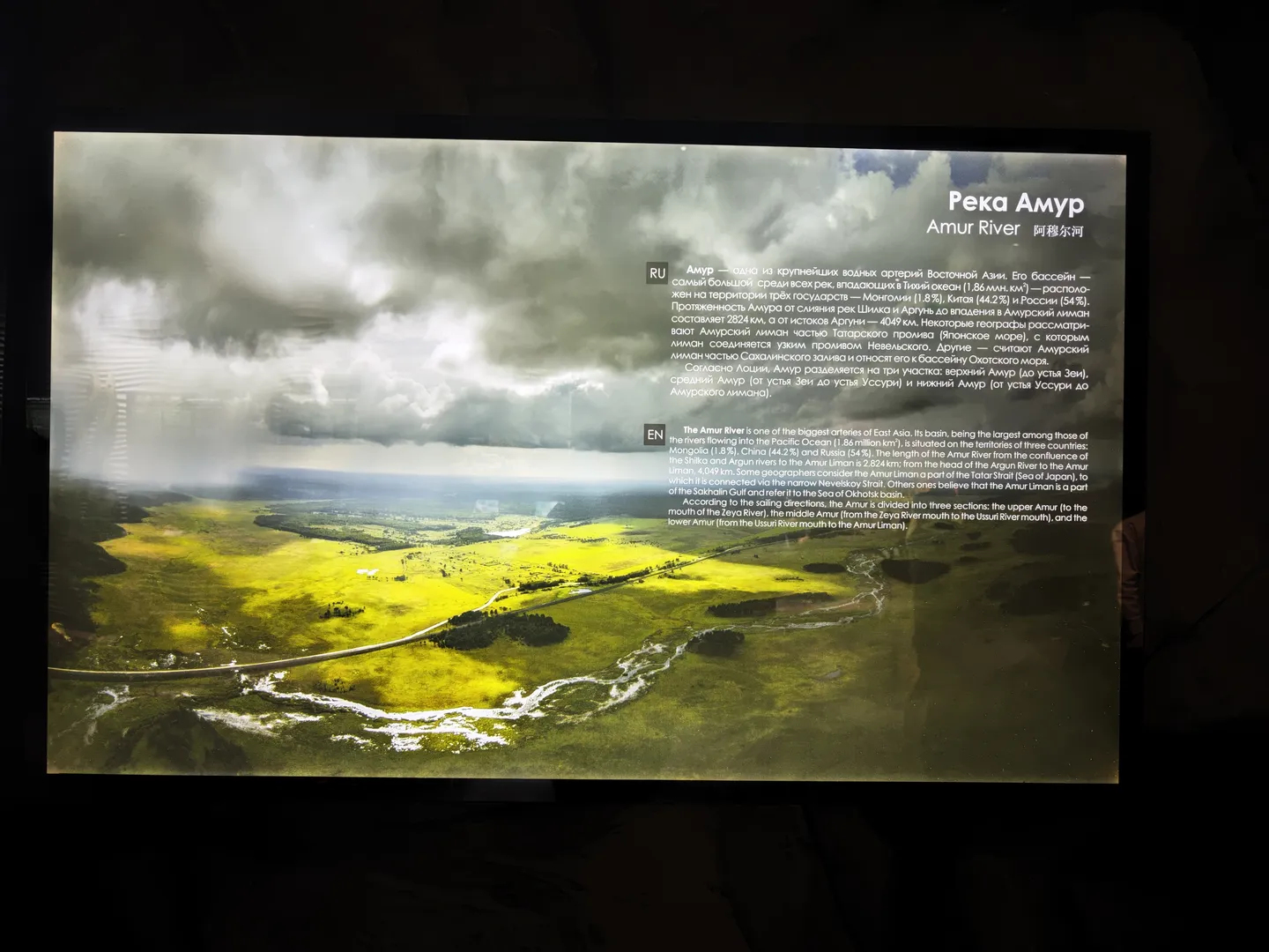 屏幕展示“Amur River”的信息,描述其地理位置和流域特征。阿穆尔河是东亚最大河流之一,流经蒙古、中国和俄罗斯。图片显示河流穿过广阔的绿色平原。