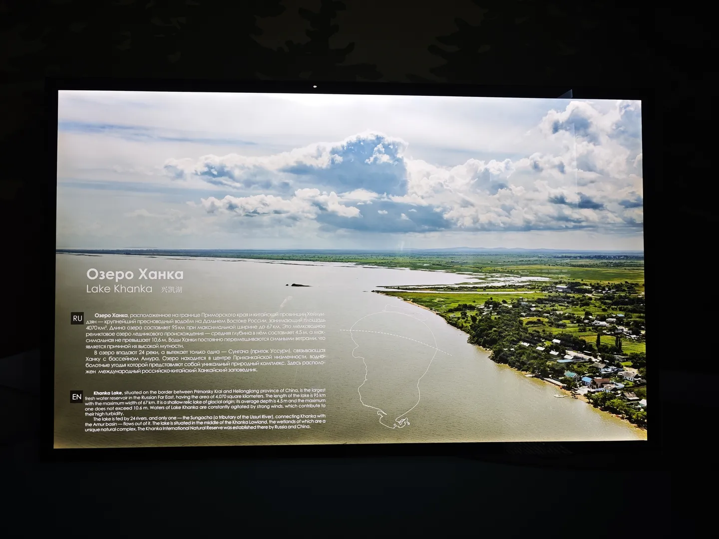 屏幕展示“Lake Khanka”的信息,描述其位于中俄边境。湖泊面积4070平方公里,长度95公里,宽度达67公里。图片显示湖泊周围的绿色景观。