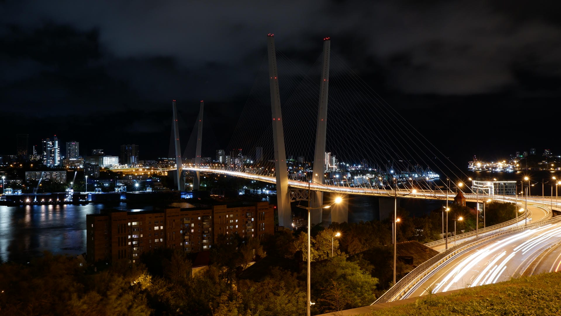 夜晚的城市大桥，桥上有车流，远处是灯火通明的城市景观。