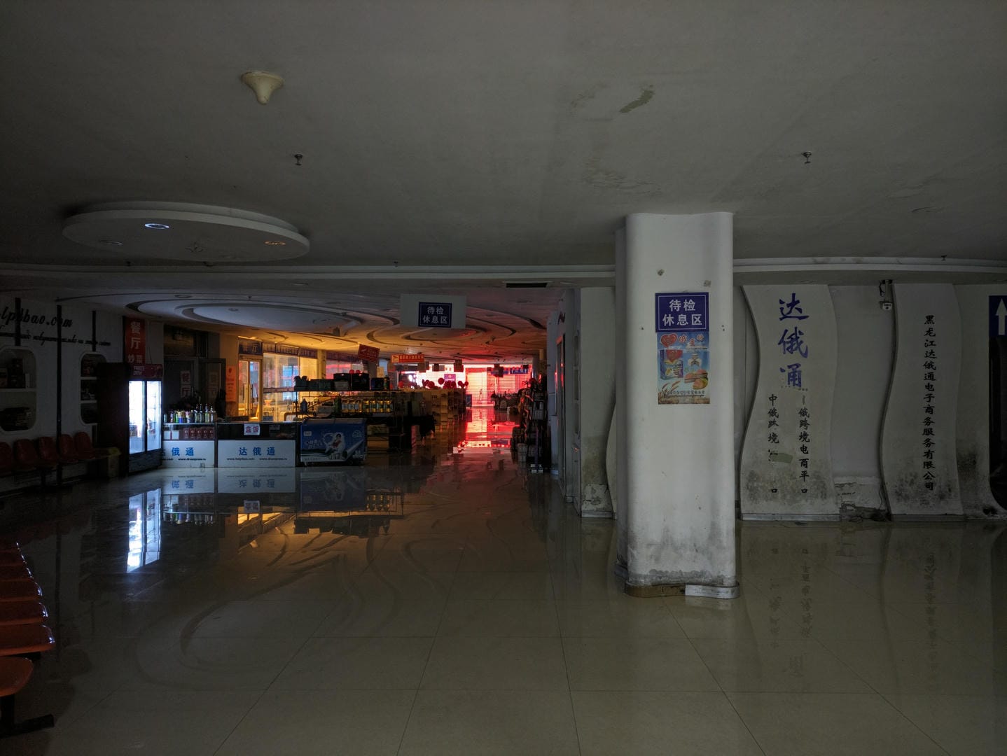 室内场景,光线较暗,有多个柜台和商品展示区,墙上有一些中文标识。