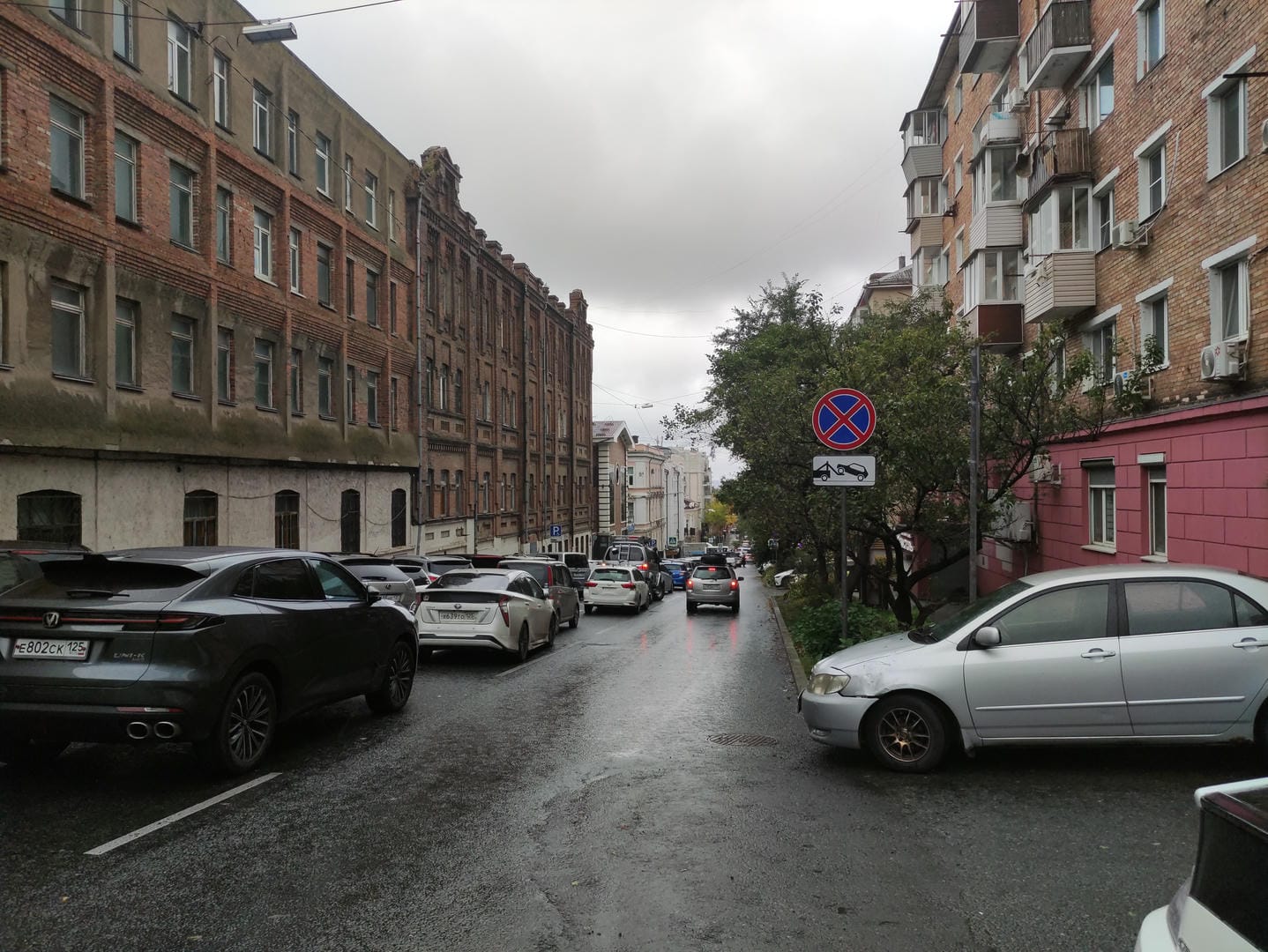 街道两旁停满了汽车,左侧建筑较为老旧,右侧建筑颜色鲜艳。