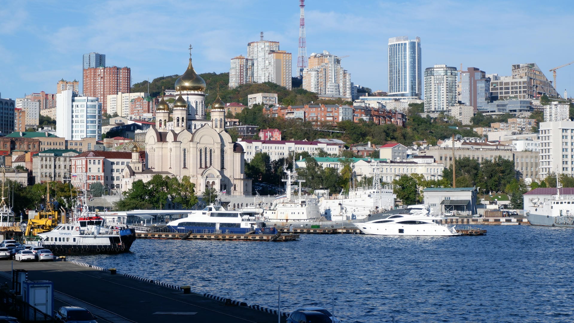 海面上有几艘船只，背景是城市的天际线，包括高楼大厦和起重机。