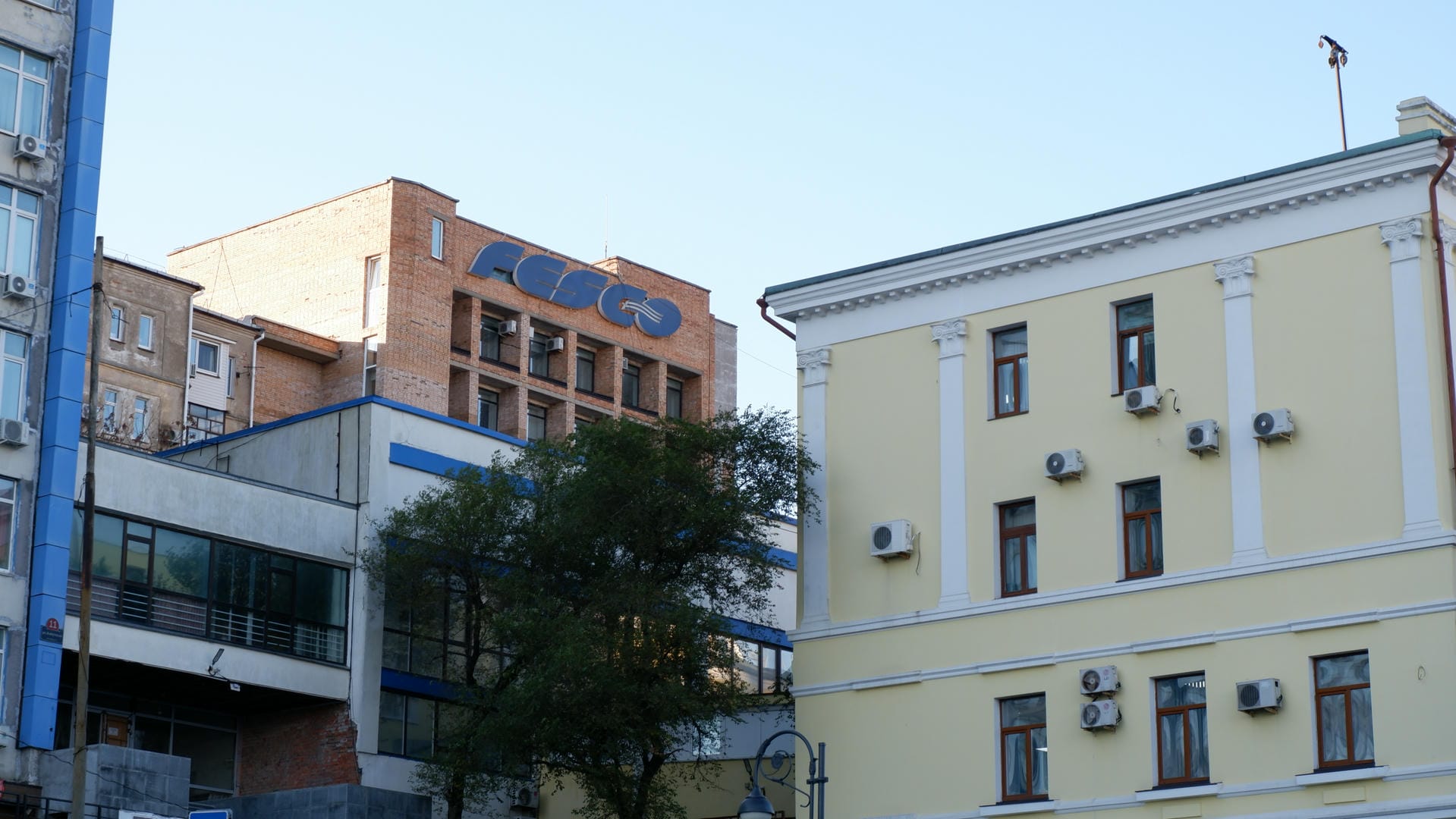 一栋建筑物的外墙，上面有“FESCO”的标志，旁边是一栋黄色的建筑。