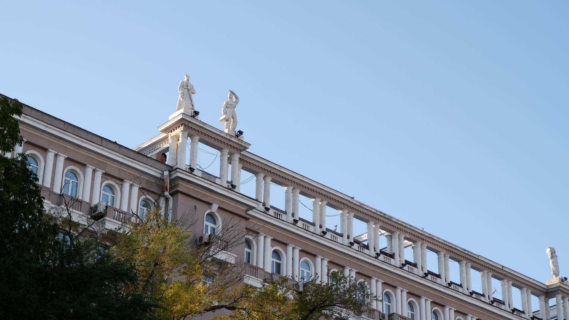 一栋建筑的顶部装饰着两座白色雕像，建筑风格古典。