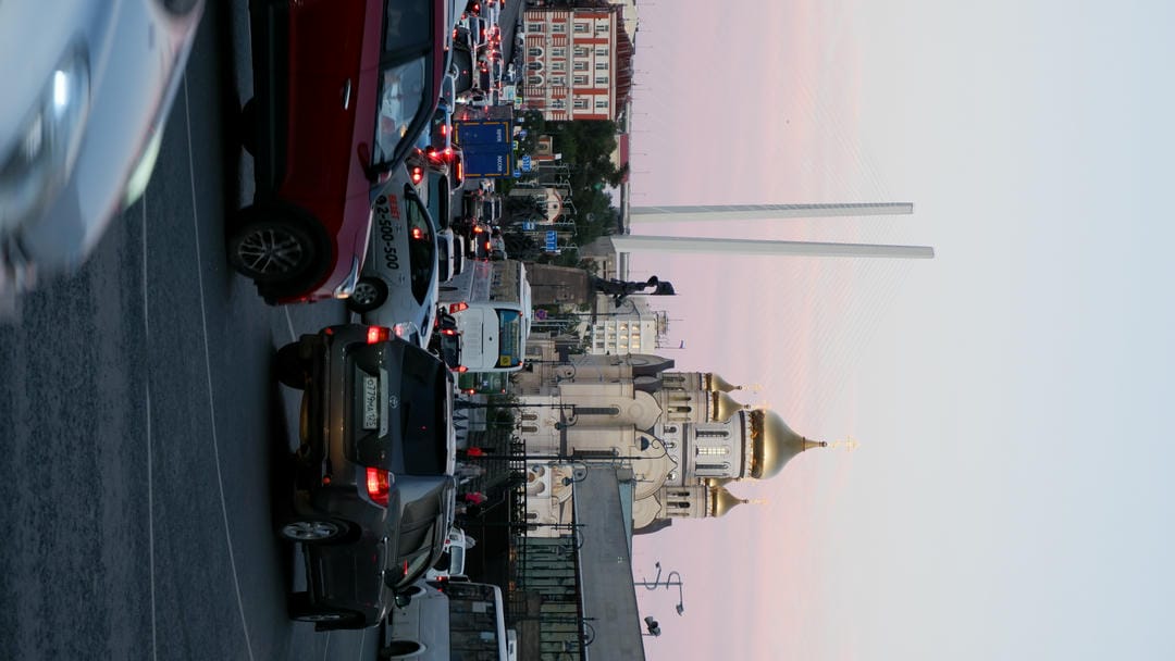 一座金色圆顶的教堂，前方道路上有许多车辆，天空呈现黄昏的颜色。