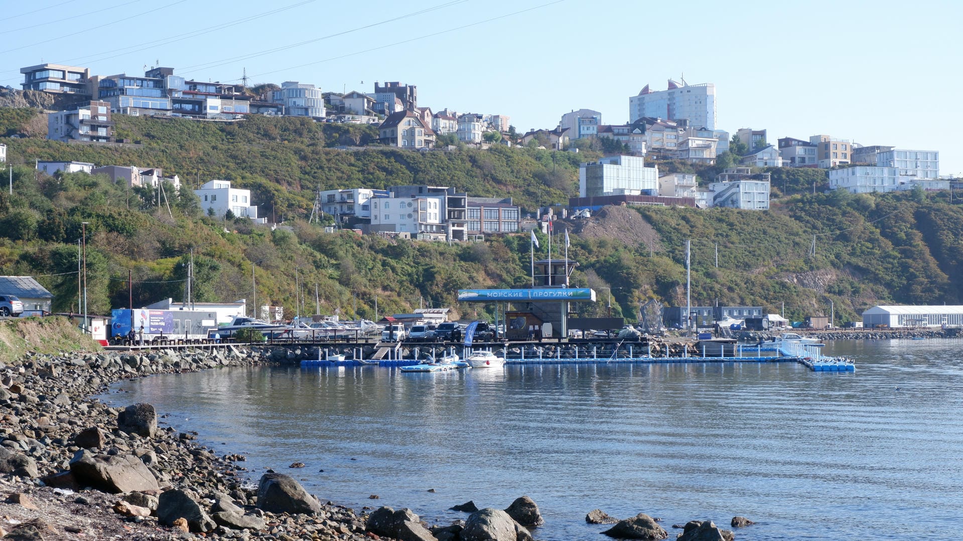 海边山坡上分布着许多建筑，下方有一个码头，停泊着一些船只。