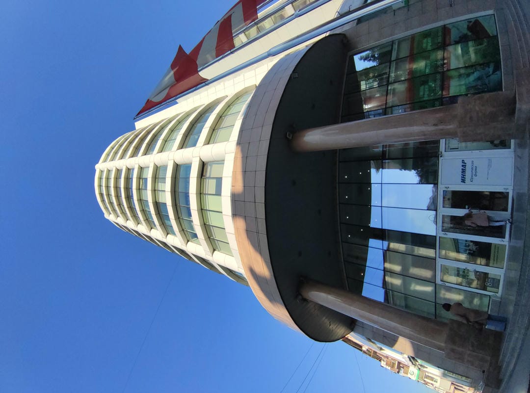 一座现代建筑,正面有玻璃幕墙,入口处有两根柱子,旁边站着一个人。