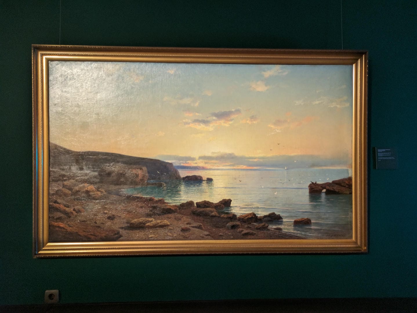 一幅描绘海岸日落景象的画作,画面中有岩石、沙滩和宁静的海面。