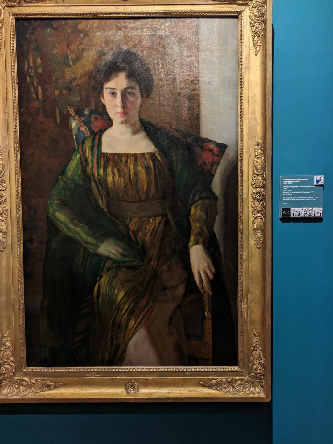 画框内展示了一幅女性肖像画,她穿着绿色的衣服,坐在椅子上。