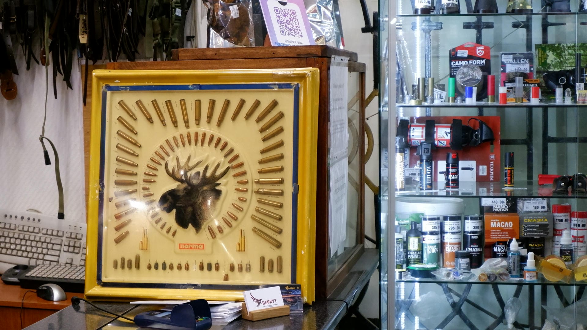 一张展示子弹排列成鹿头图案的装饰板，背景是狩猎用品店。