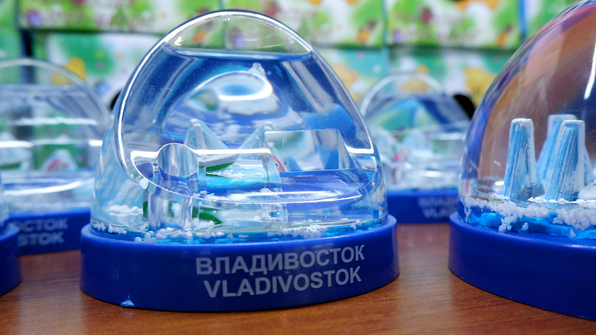 透明的水晶球内展示着微型建筑模型，底部印有“VLADIVOSTOK”字样。