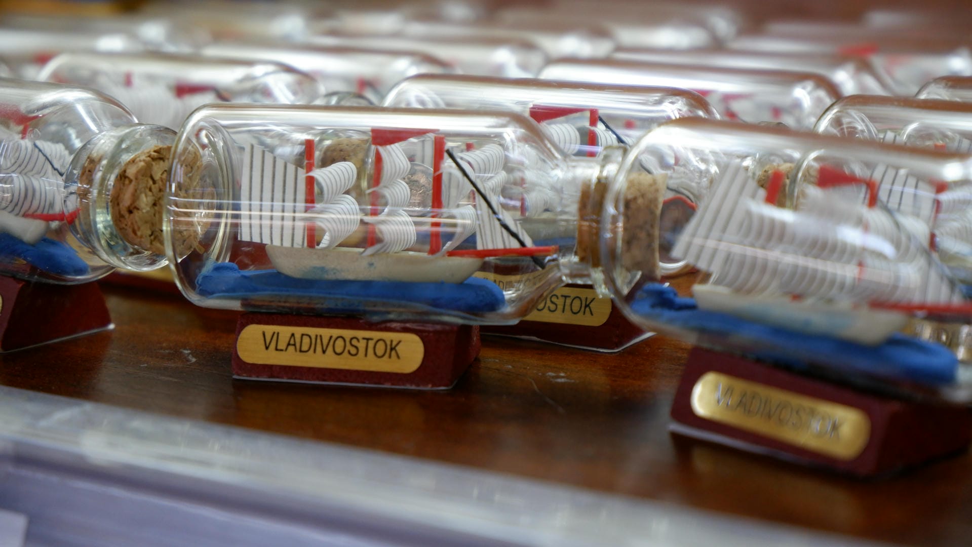 一排装在瓶子里的微型帆船模型，标签上写着“VLADIVOSTOK”。