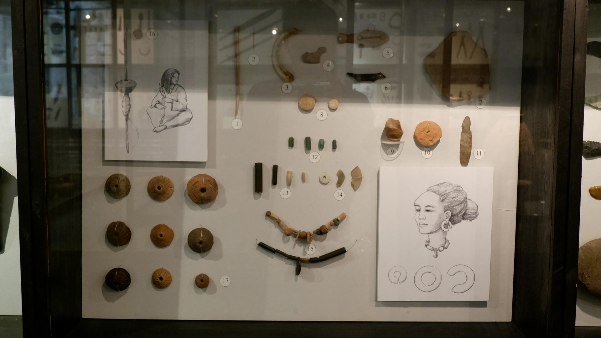 一个展示柜内摆放着各种古代饰品和物品，包括项链、珠子和雕刻品。
