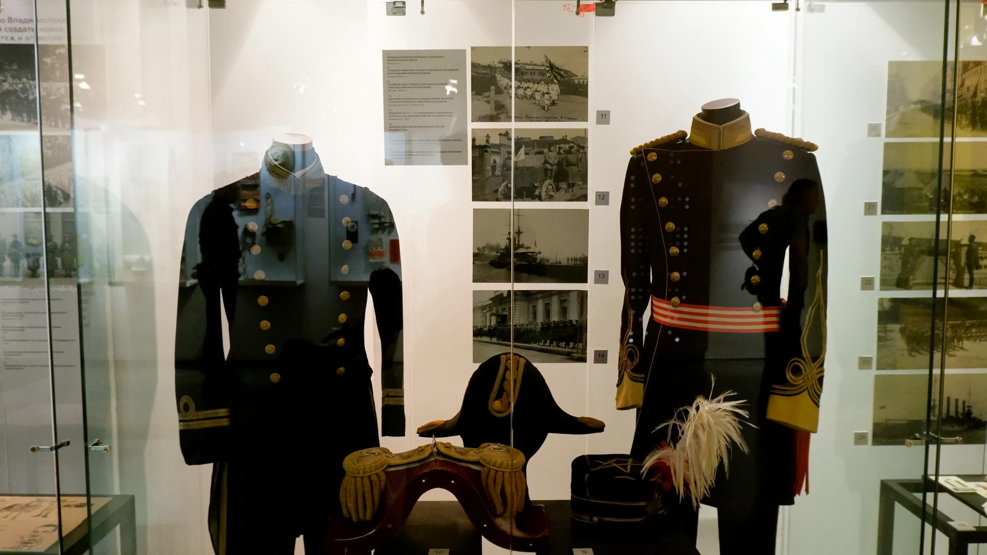 两套军装和一顶军帽展示在玻璃柜中，旁边有历史照片。