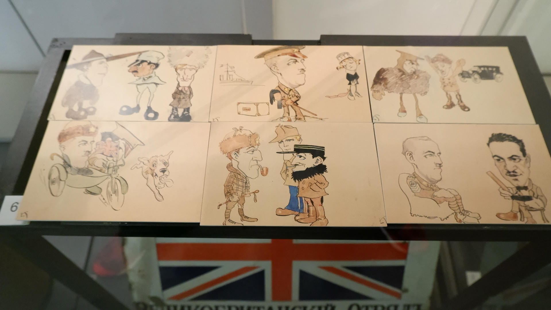 九张卡通画展示在玻璃柜中，下方有英国国旗标志。