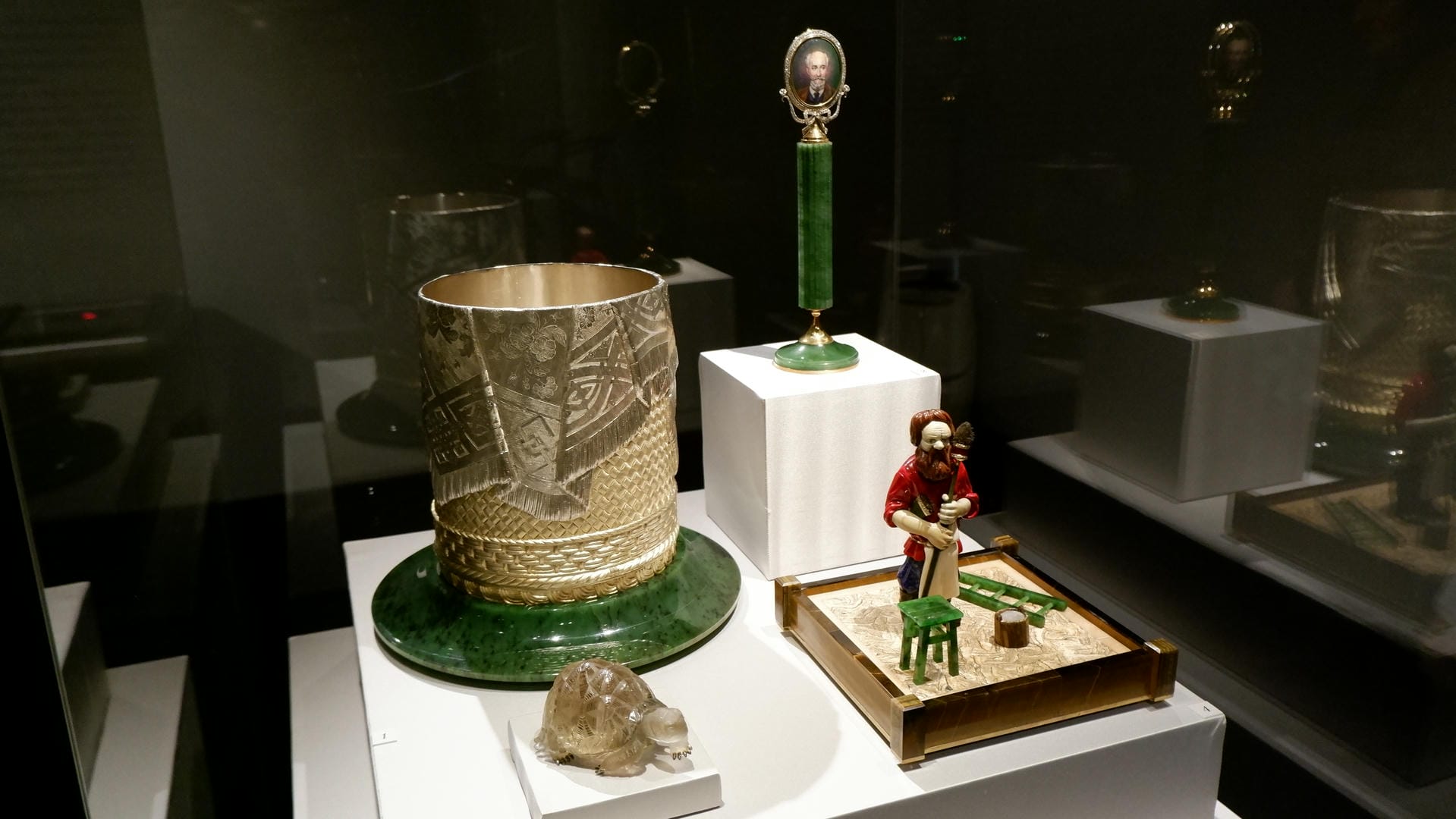 展示柜中有绿色底座的金属容器、绿色柱形物品和一个小人模型。