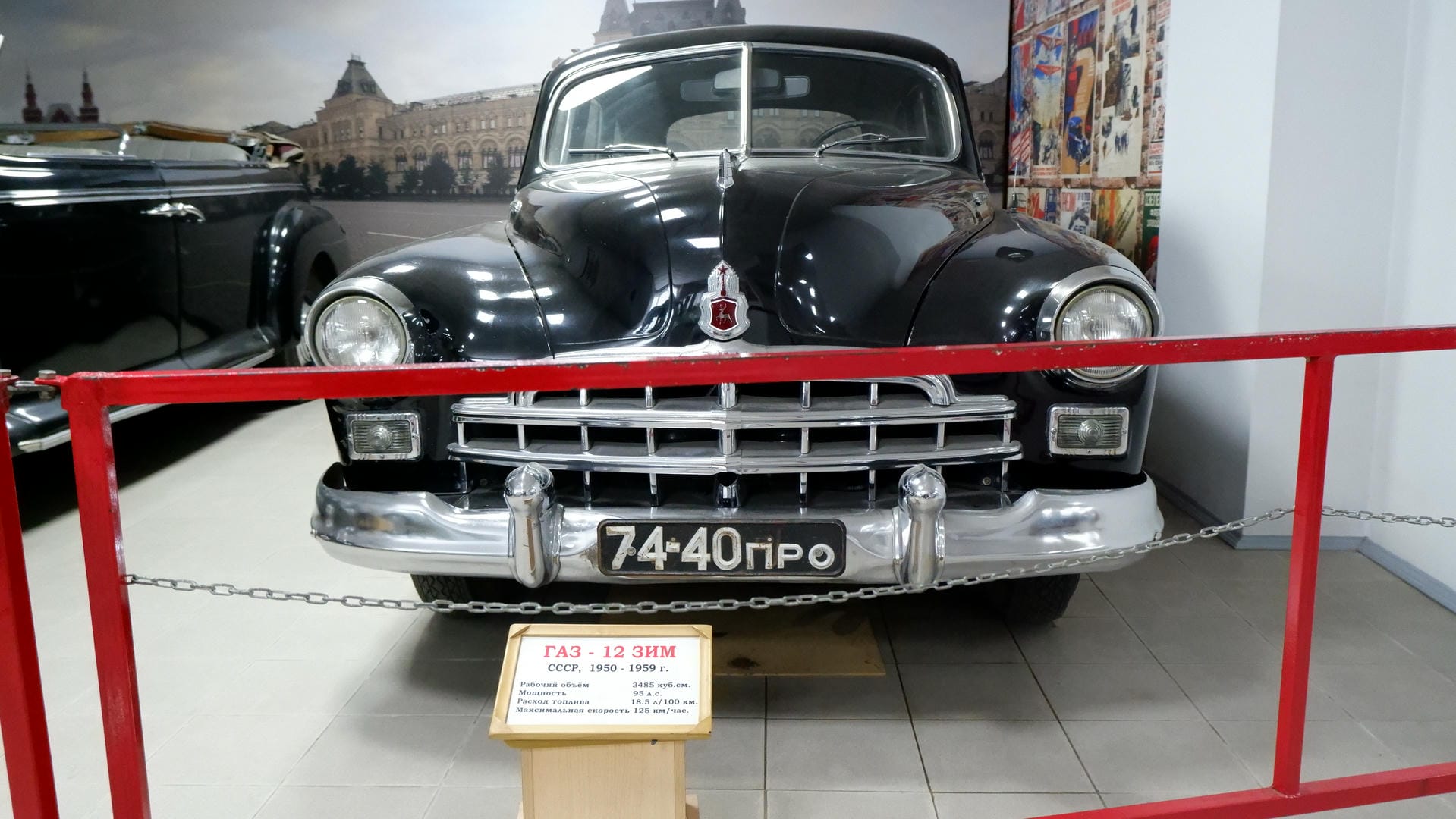 一辆黑色的老式汽车，车牌上写着“74-40ПРО”，前部有红色围栏保护。
