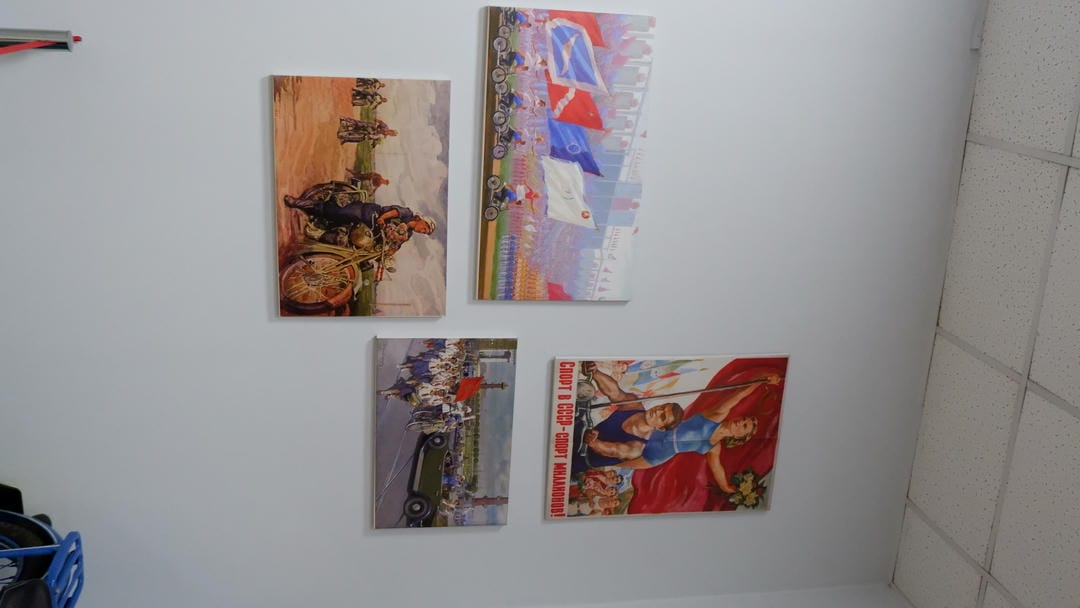 墙上挂着四幅画，描绘了不同场景，包括体育赛事和军事活动。