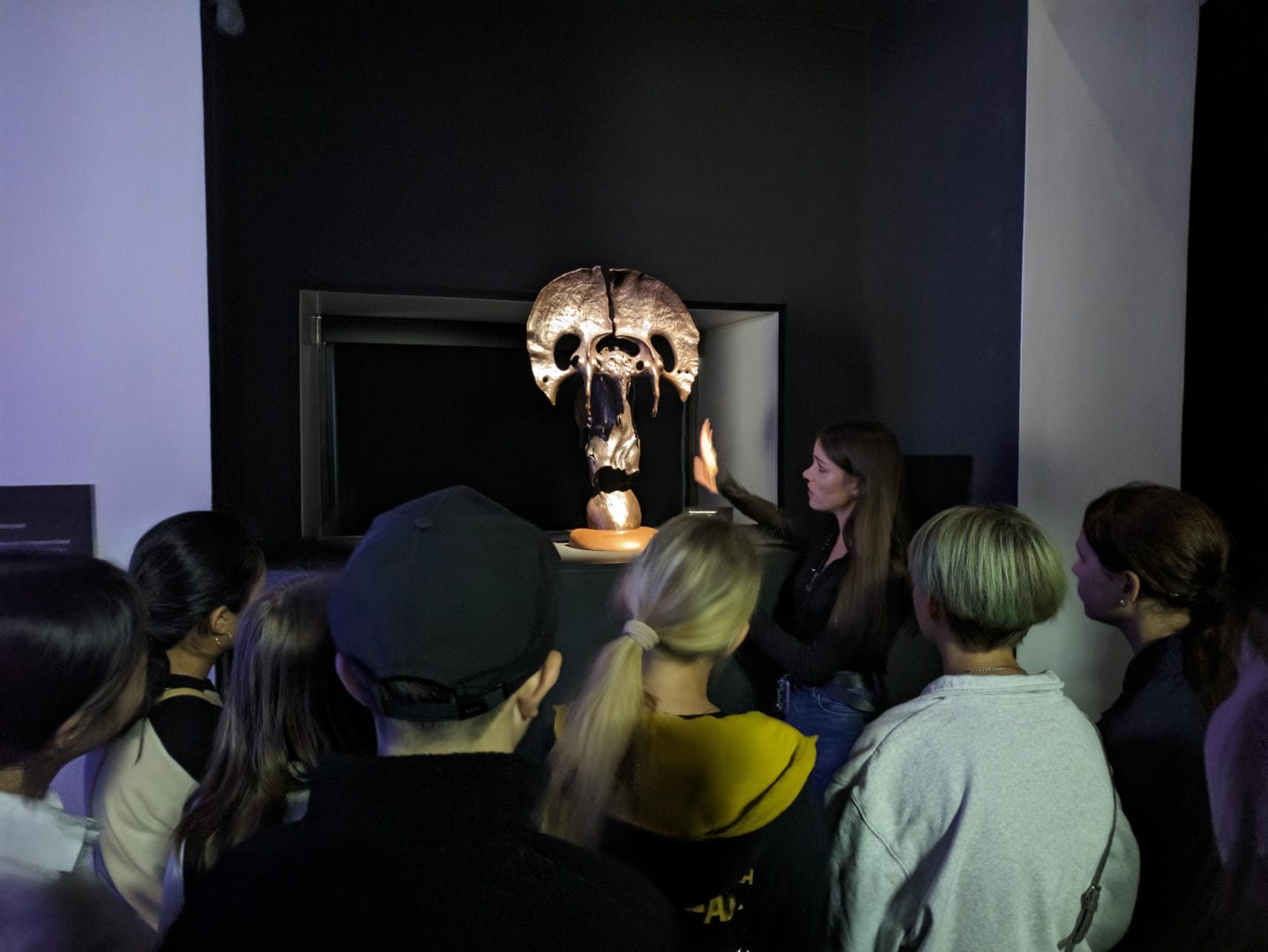 一群人在听讲解员介绍一个头骨化石展品。