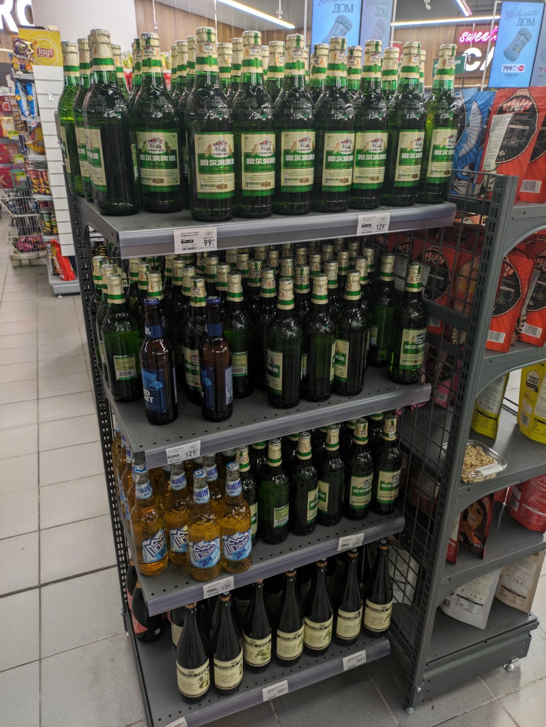 超市货架上摆放着各种品牌的啤酒瓶。