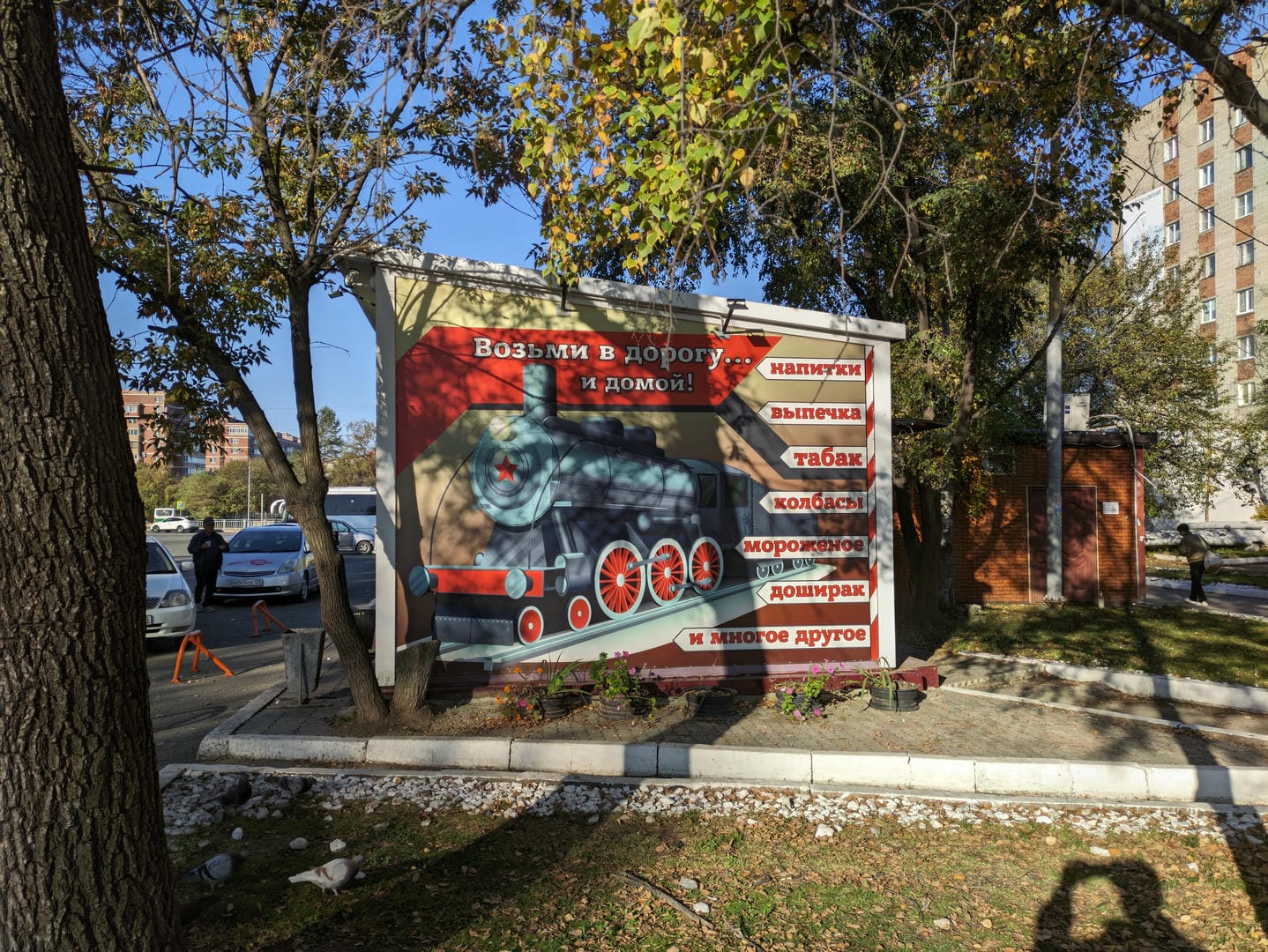 户外广告牌上画着一列火车,周围有俄文和中文标识。