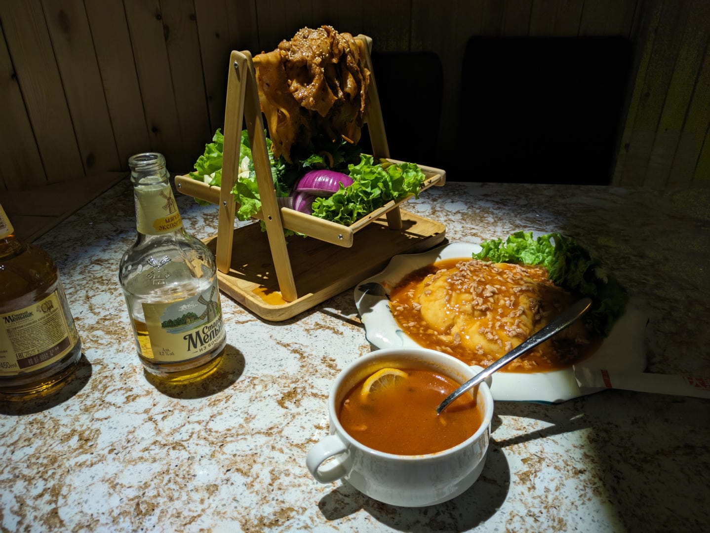 餐桌上有一杯汤、一份肉菜和一瓶酒。