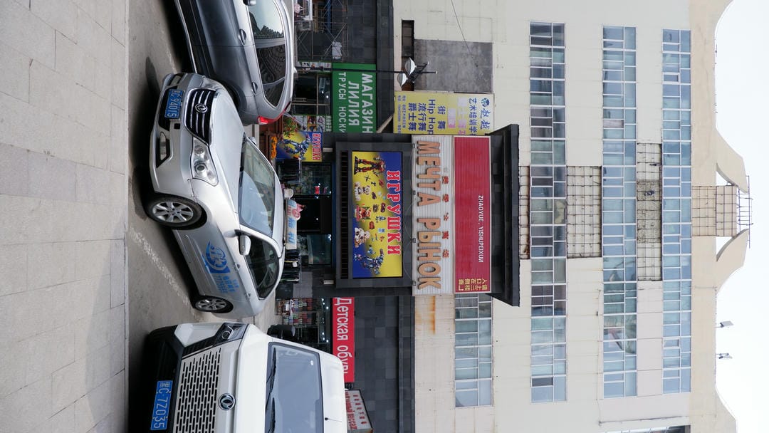 一栋多层建筑，正面有多个窗户，下方有一个标牌写着“МЕЧТА РЫНОК”，旁边还有其他商店的招牌。