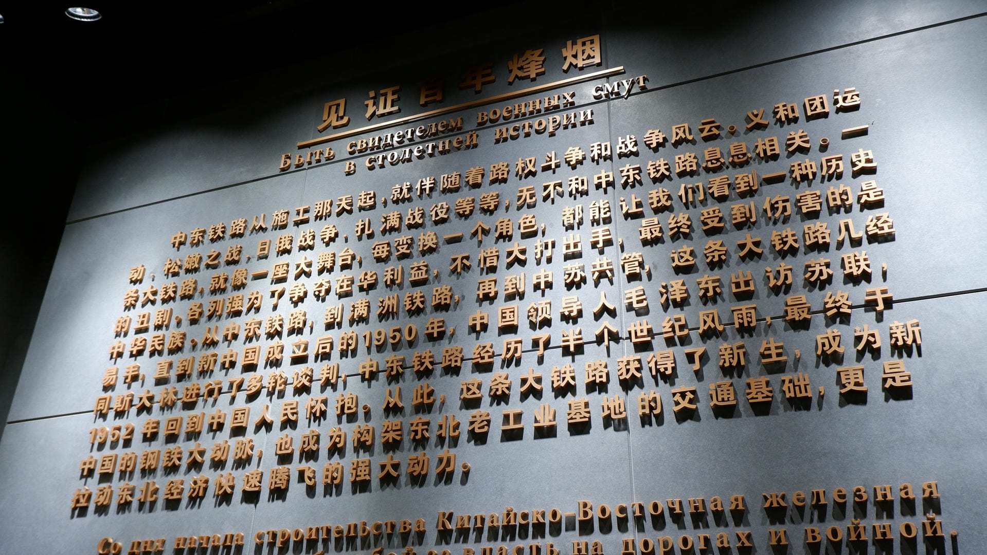 墙上有金色文字介绍中东铁路的历史，背景是黑色的。