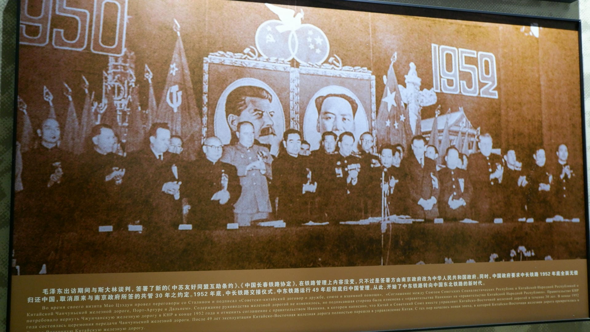 一幅历史壁画，描绘了1952年的场景，有旗帜和人物。